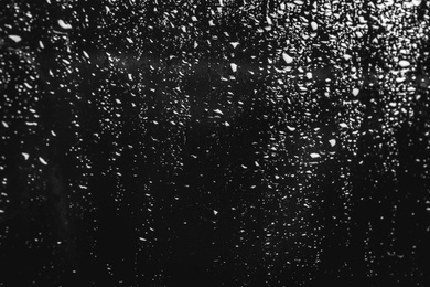 Photo of Glass with rain drops on black background