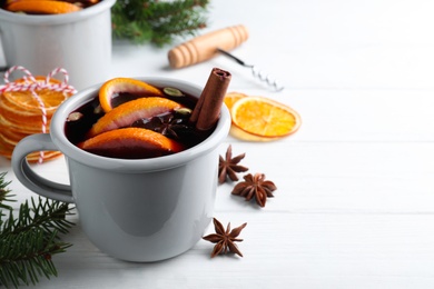 Photo of Aromatic mulled wine and ingredients on white wooden table. Space for text