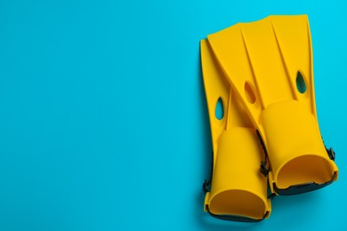 Photo of Pair of yellow flippers on light blue background, flat lay. Space for text