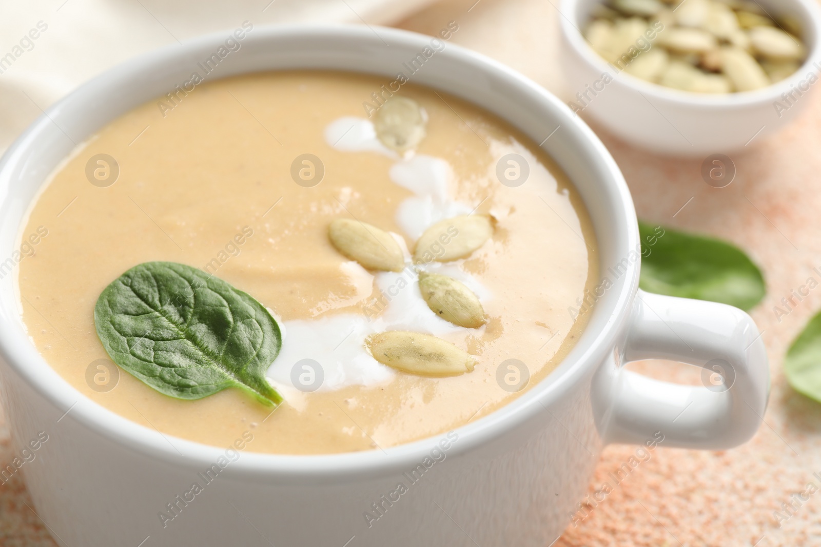 Photo of Healthy cream soup high in vegetable fats on color textured table, closeup