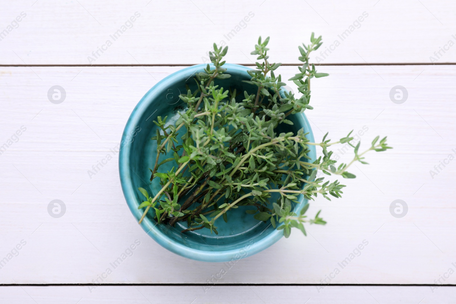 Photo of Bowl with aromatic fresh thyme on white wooden table, top view