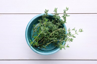 Bowl with aromatic fresh thyme on white wooden table, top view