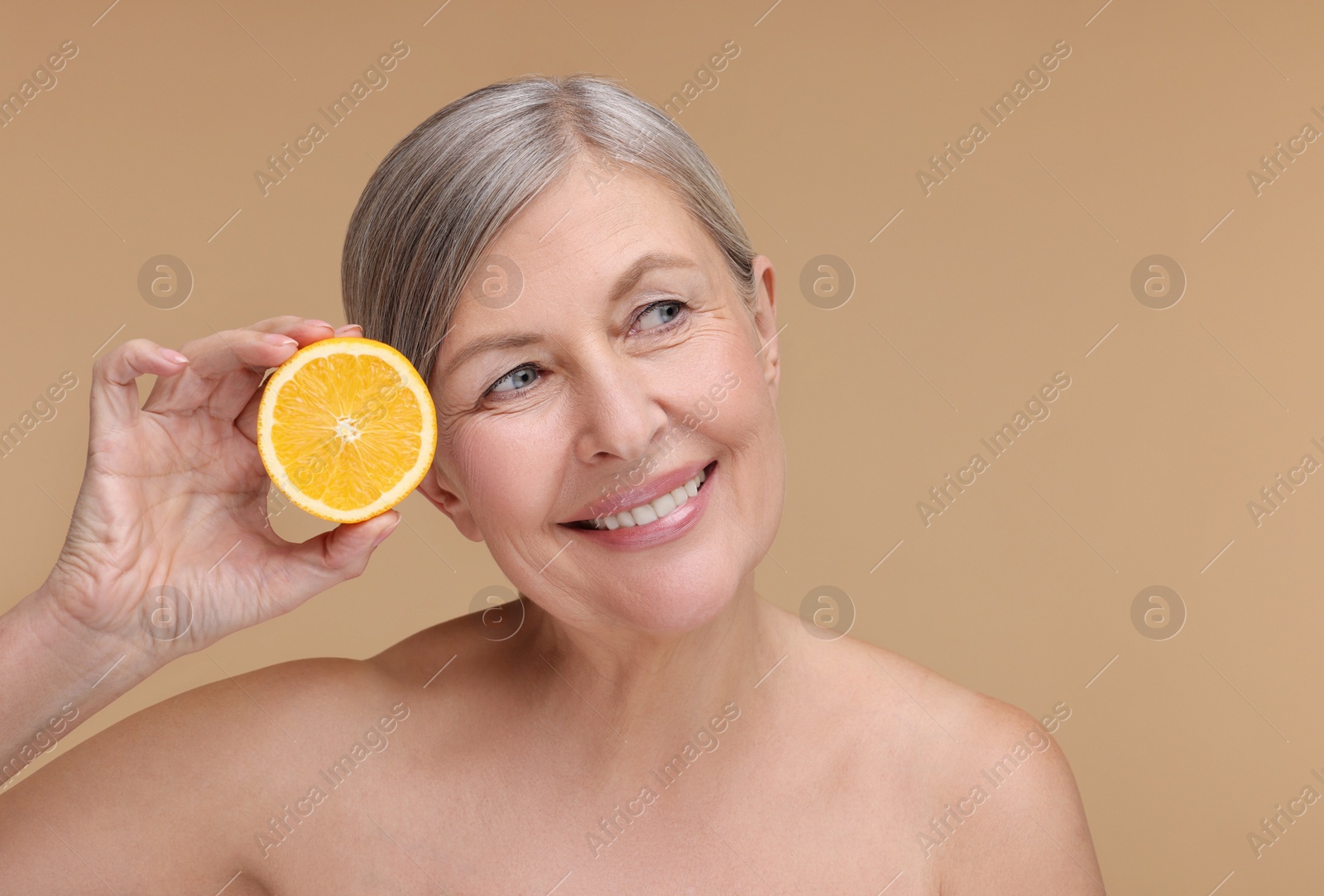 Photo of Beautiful woman with half of orange rich in vitamin C on beige background