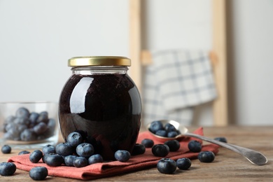 Jar of blueberry jam and fresh berries on wooden table