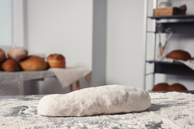 Fresh dough with flour on table in kitchen