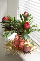 Vase with bouquet of beautiful Protea flowers on window sill indoors