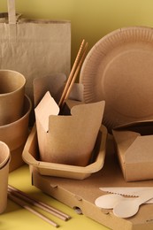 Eco friendly food packaging. Paper containers, tableware and bag on pale yellow background