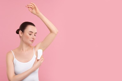 Photo of Beautiful woman applying deodorant on pink background, space for text
