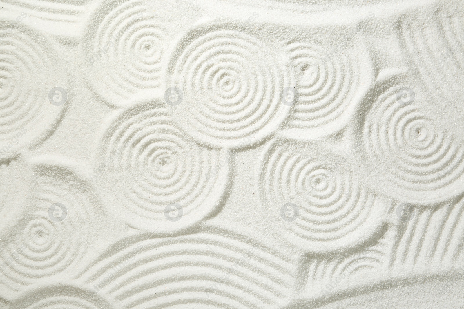 Photo of Zen rock garden. Circle patterns on white sand, top view