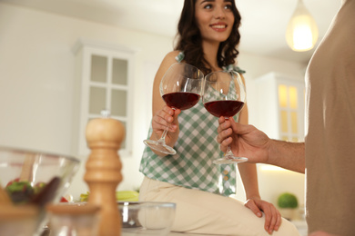 Photo of Lovely young couple with glasses of wine cooking together at kitchen, closeup