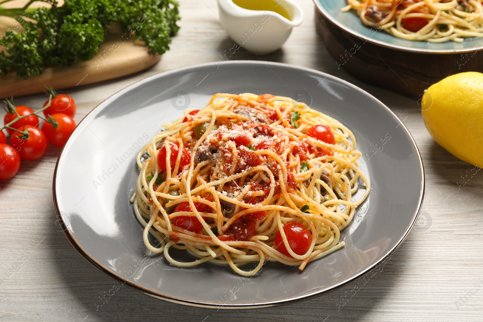 Photo of Delicious pasta with anchovies, tomatoes and parmesan cheese on white wooden table