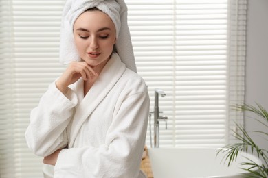Beautiful woman wearing white robe in bathroom, space for text