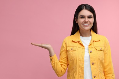 Special promotion. Happy woman holding something on pink background, space for text