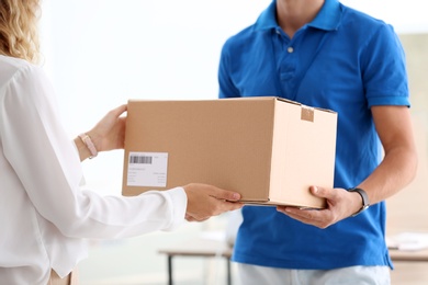 Young woman receiving parcel from courier in office