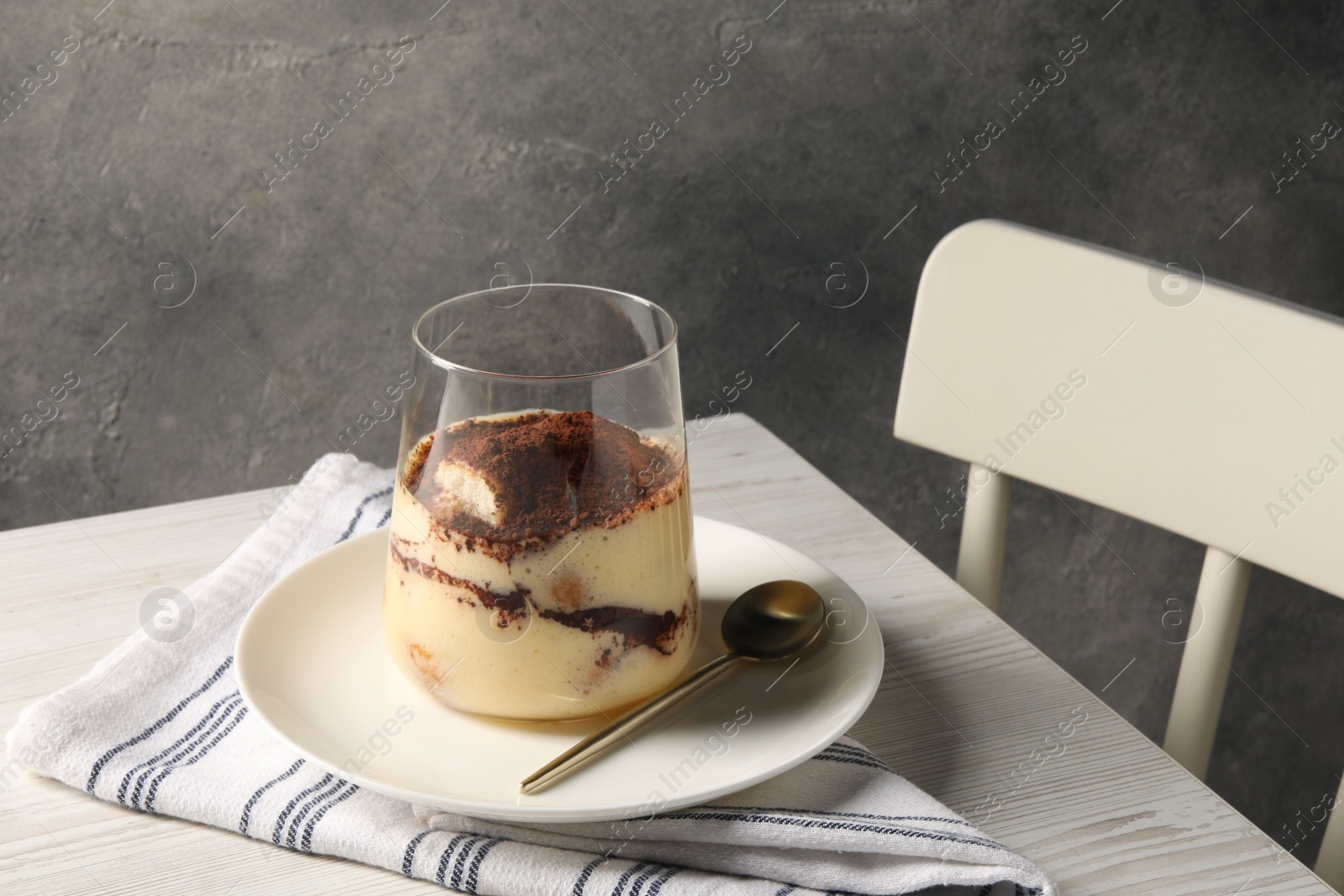 Photo of Delicious tiramisu in glass on white wooden table