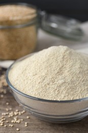 Photo of Glass bowl with quinoa flour and seeds on table, closeup