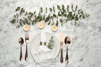 Photo of Beautiful place setting with candles and eucalyptus on white marble table, flat lay