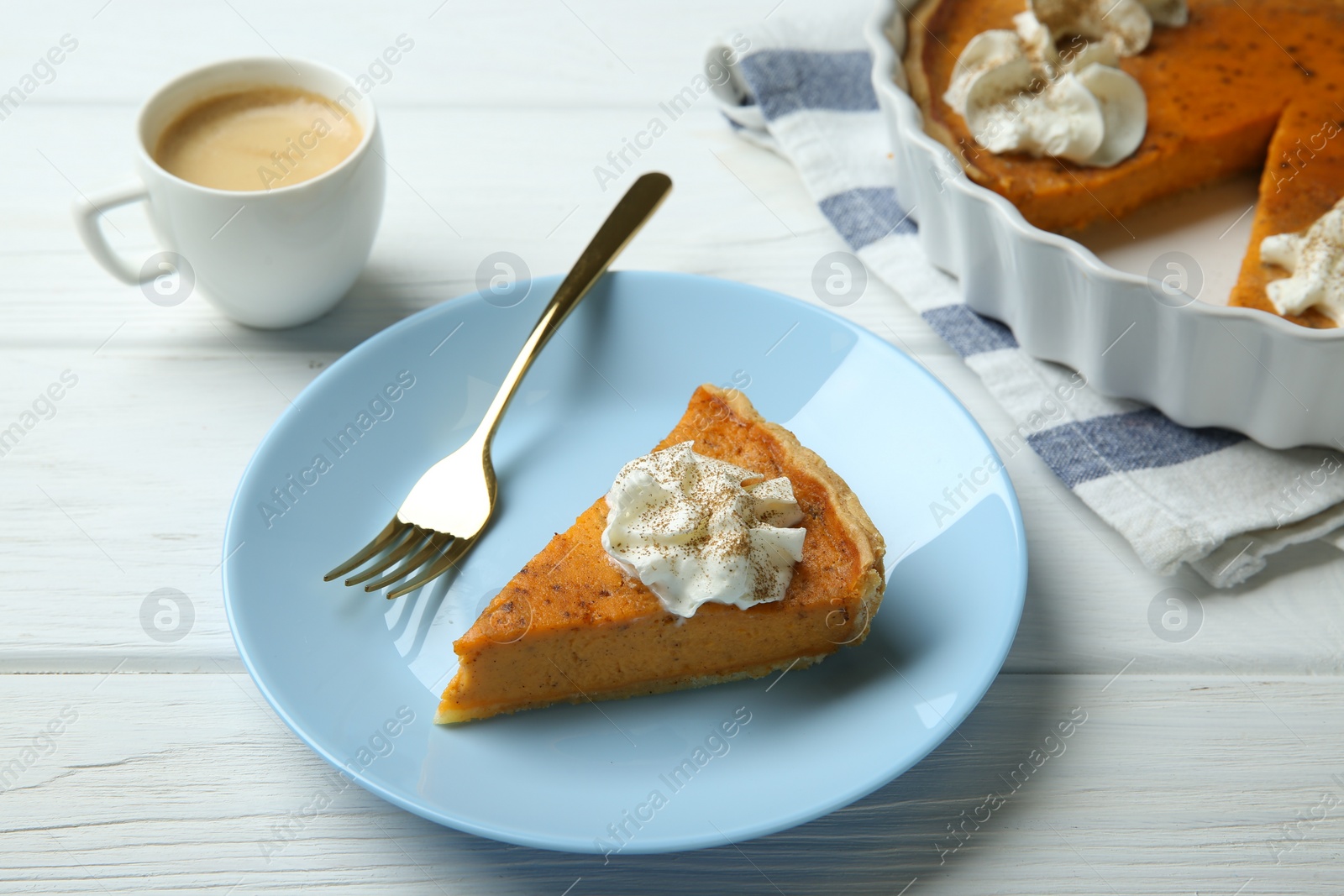 Photo of Delicious pumpkin pie with whipped cream, fork and cup of coffee on white wooden table