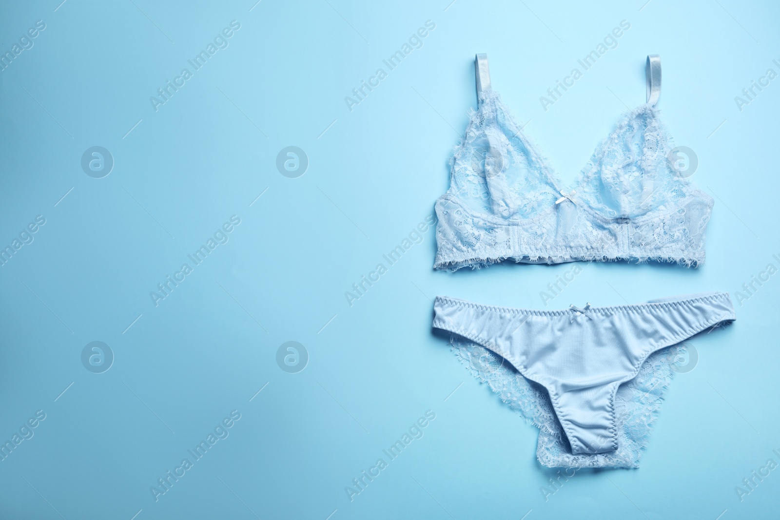 Photo of Elegant women's underwear on light blue background, flat lay. Space for text