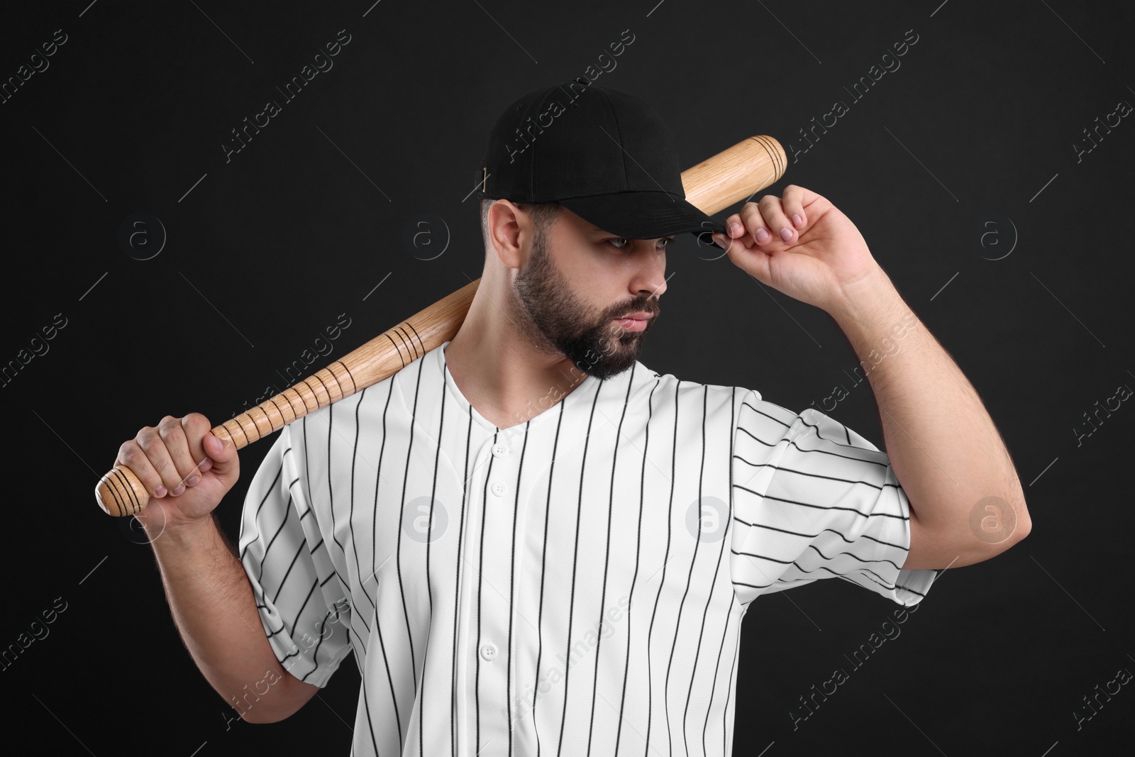 Photo of Man in stylish baseball cap holding bat on black background