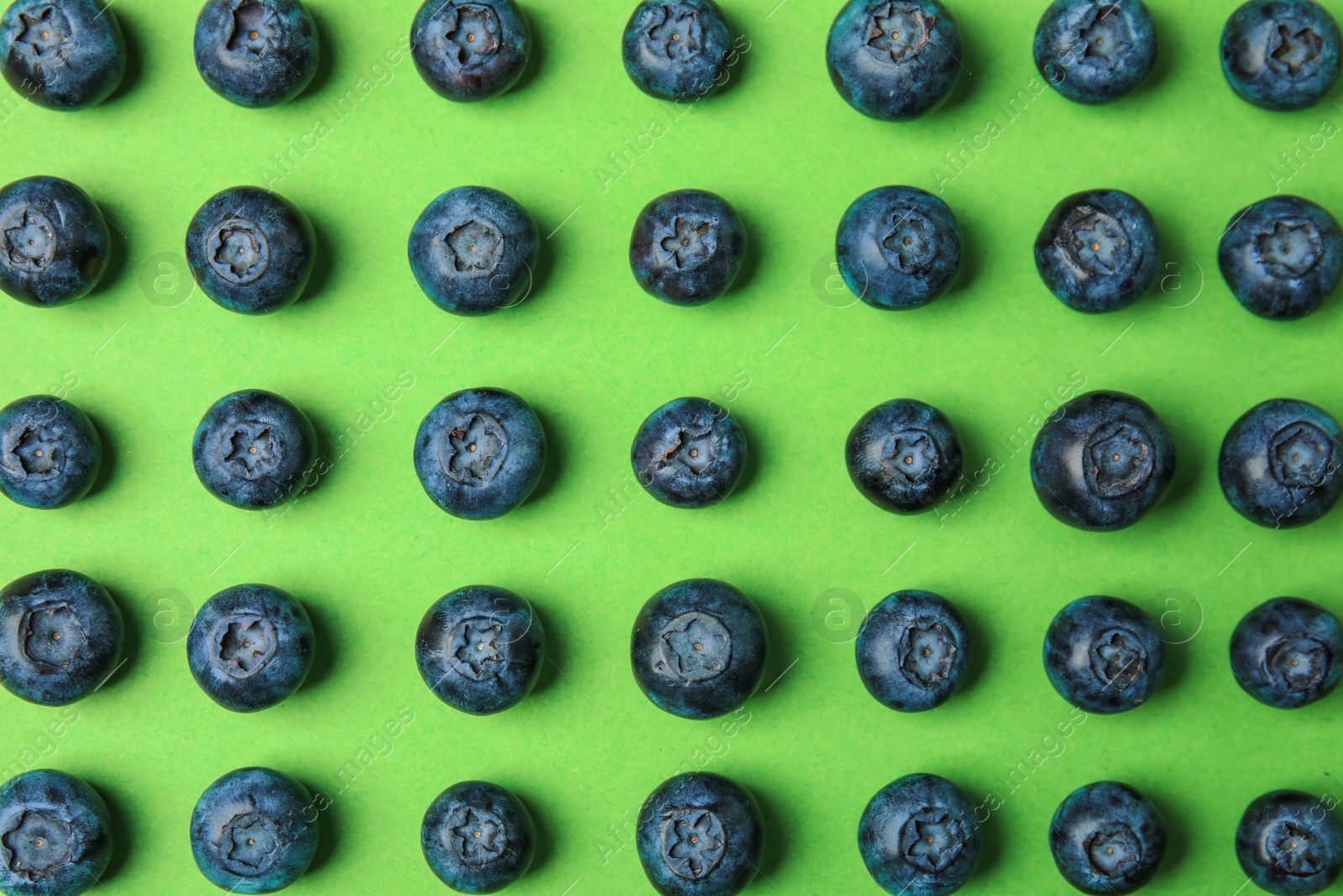 Photo of Tasty ripe blueberries on green background, flat lay