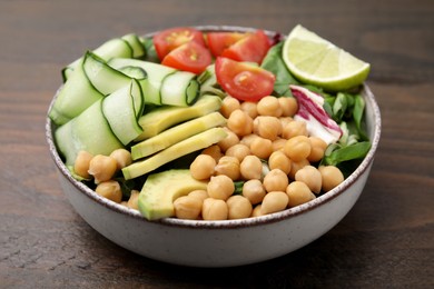 Tasty salad with chickpeas and vegetables on wooden table, closeup