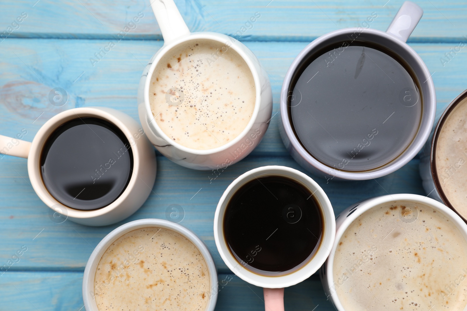 Photo of Many cups of different coffee drinks on light blue wooden table, flat lay