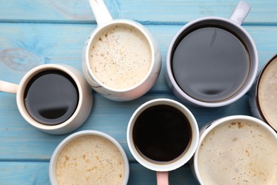 Many cups of different coffee drinks on light blue wooden table, flat lay