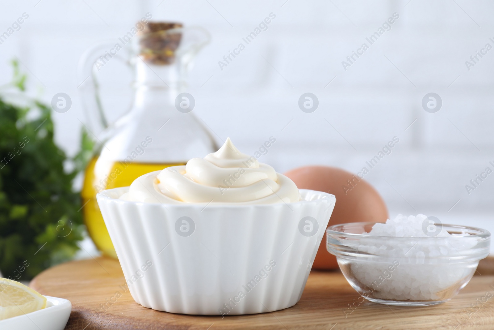 Photo of Fresh mayonnaise sauce in bowl and ingredients on table