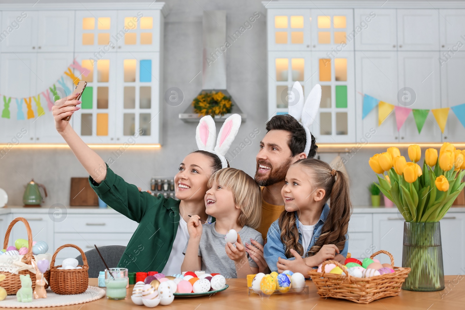 Photo of Family making selfie while painting Easter eggs at table in kitchen