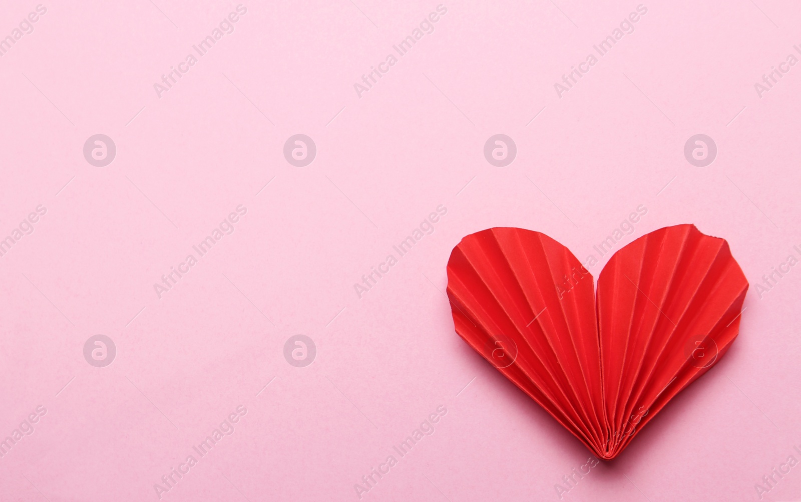 Photo of Red decorative paper heart on pink background, top view. Space for text