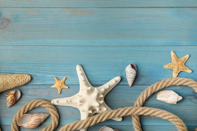 Photo of Beautiful sea stars, shells and rope on blue wooden background, flat lay. Space for text