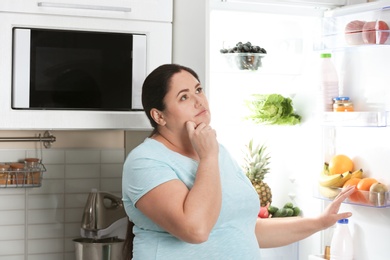 Woman choosing food from fridge at kitchen. Healthy diet