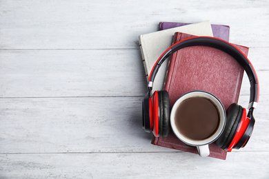 Photo of Books, coffee and headphones on white wooden table, top view. Space for text