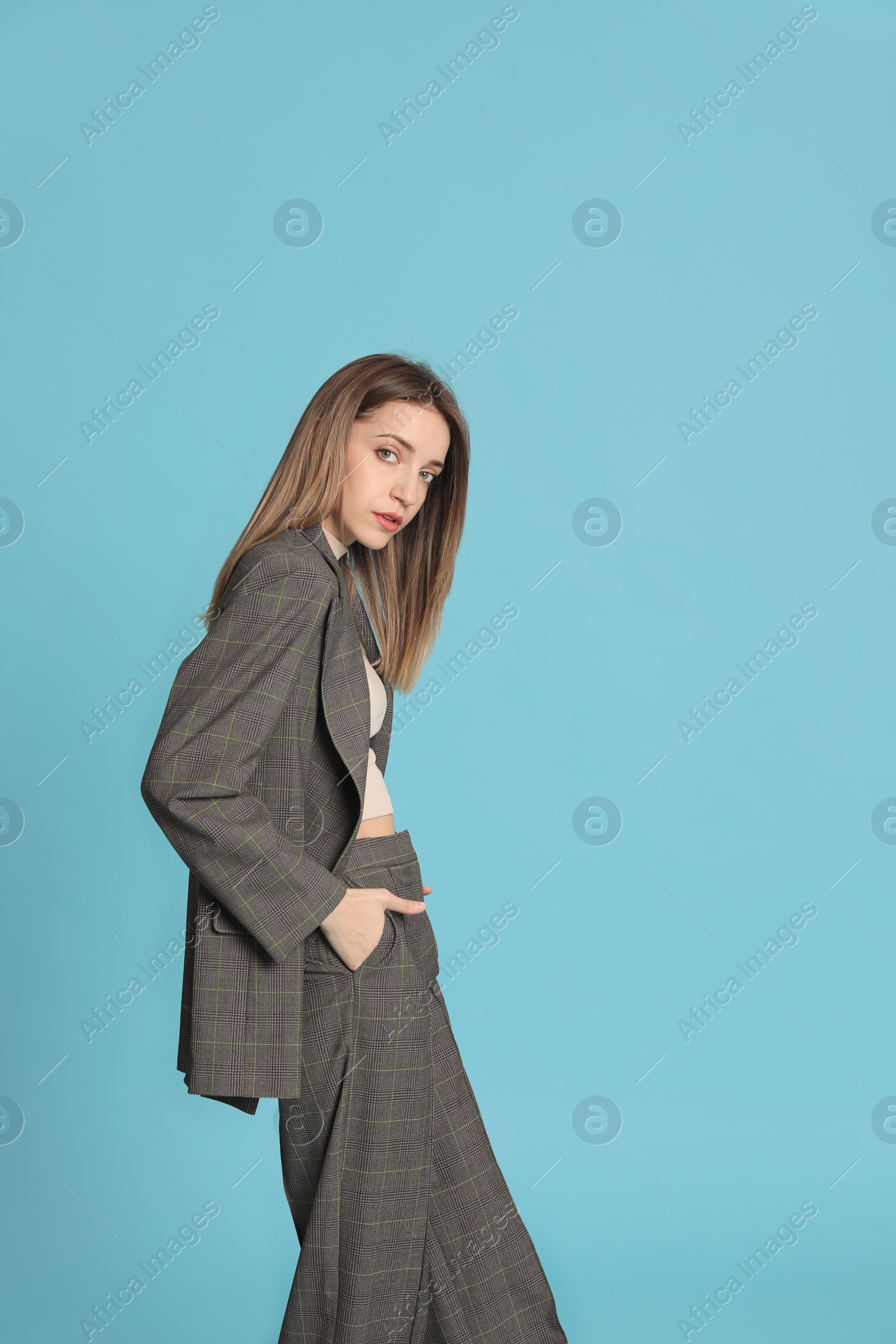 Photo of Portrait of beautiful young woman in fashionable suit on light blue background, space for text. Business attire