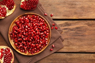 Photo of Ripe juicy pomegranates and grains on wooden table, flat lay