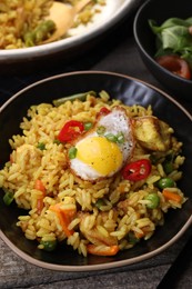 Tasty rice with meat, egg and vegetables in bowl served on wooden table