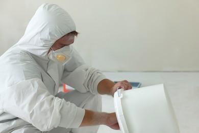 Photo of Decorator holding white bucket with paint indoors