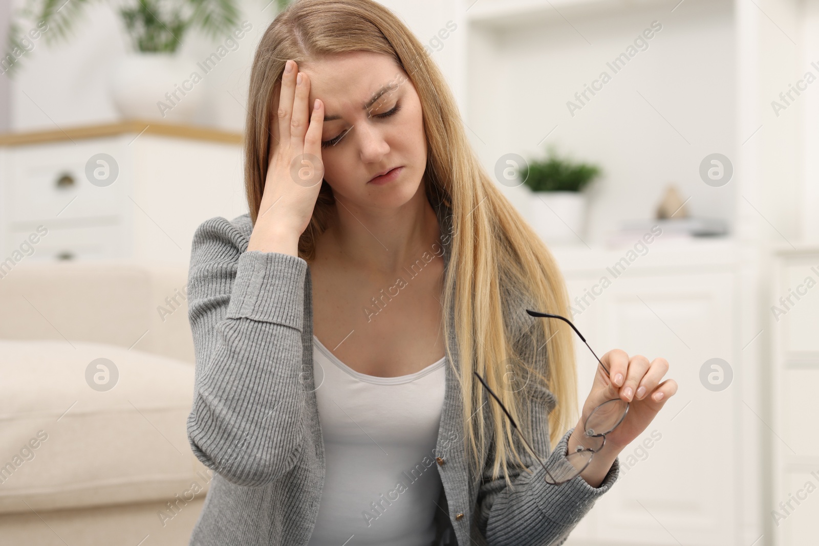 Photo of Overwhelmed young woman with glasses suffering from headache at home