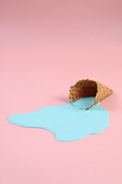 Melted ice cream and wafer cone on pink background, space for text