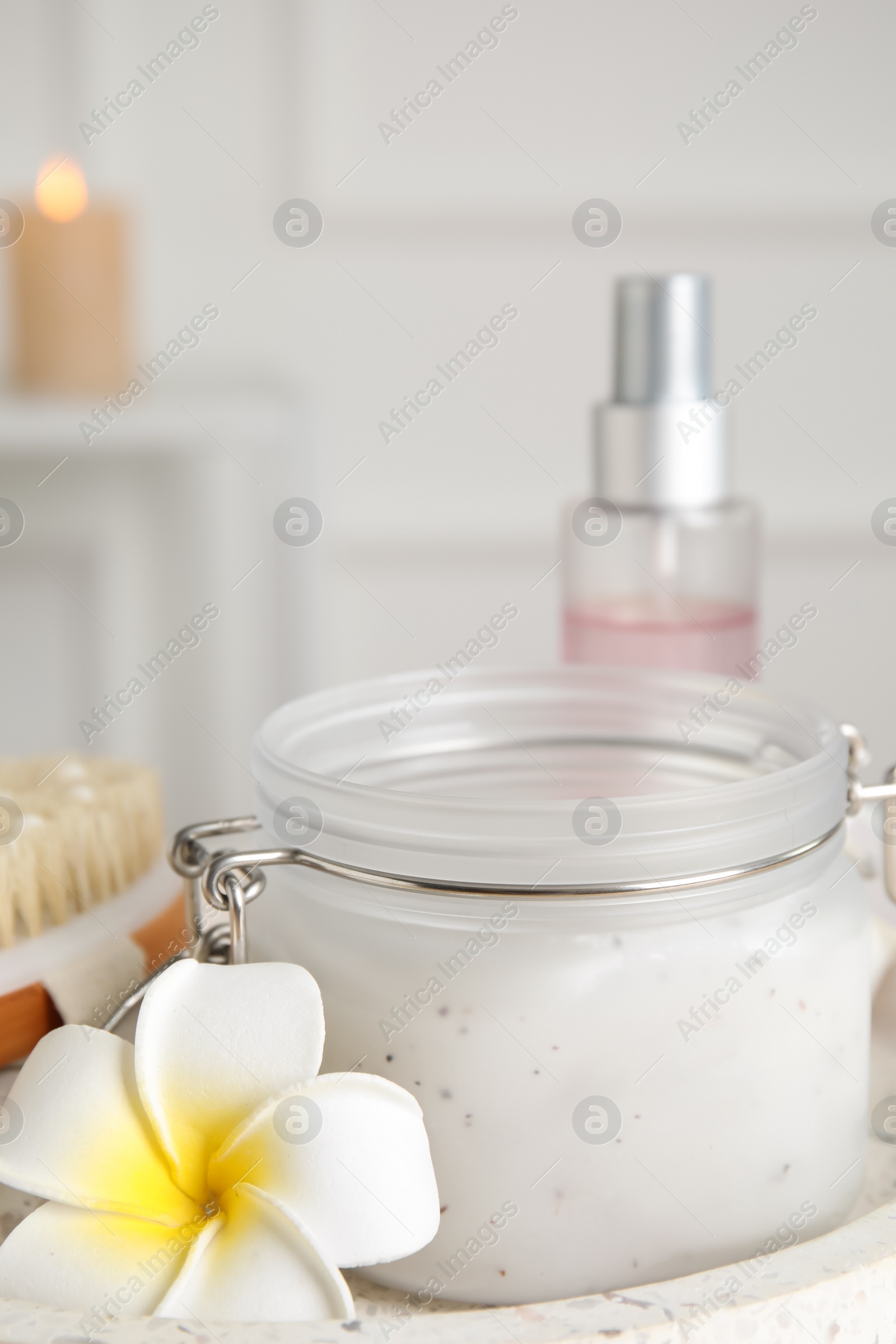 Photo of Jar of salt scrub and plumeria flower on tray