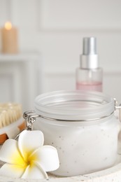 Jar of salt scrub and plumeria flower on tray