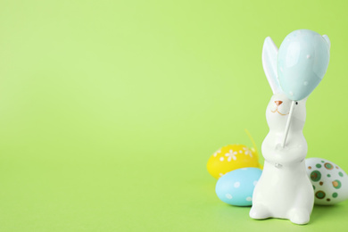 Easter bunny figure and dyed eggs on green background. Space for text