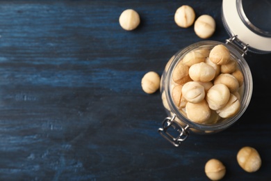 Photo of Jar with shelled organic Macadamia nuts and space for text on blue wooden background, top view