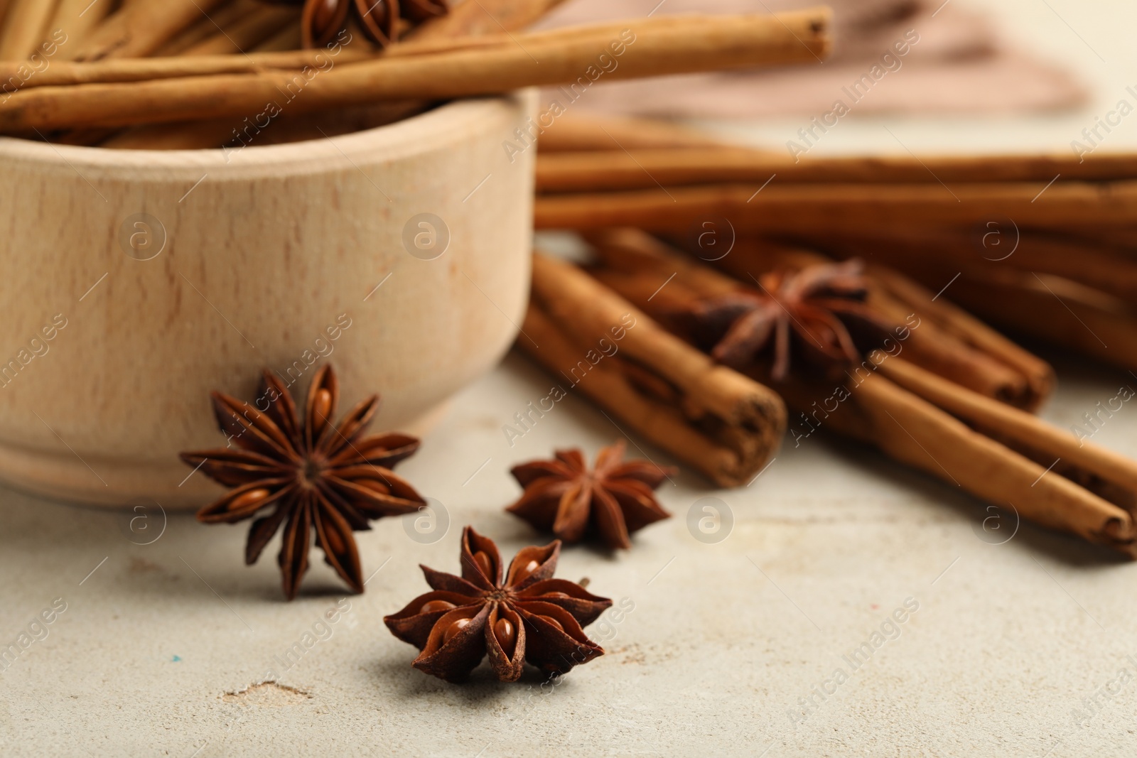 Photo of Bowl with cinnamon sticks and star anise on light table, closeup