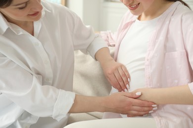 Photo of Doula taking care of pregnant woman at home, closeup. Preparation for child birth