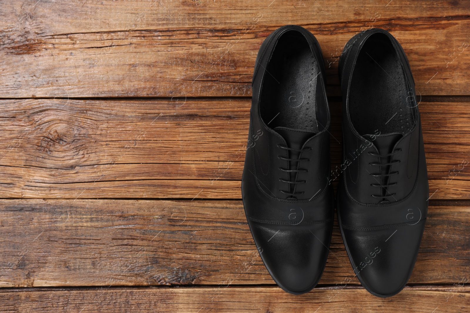 Photo of Pair of black leather men shoes on wooden background, top view. Space for text