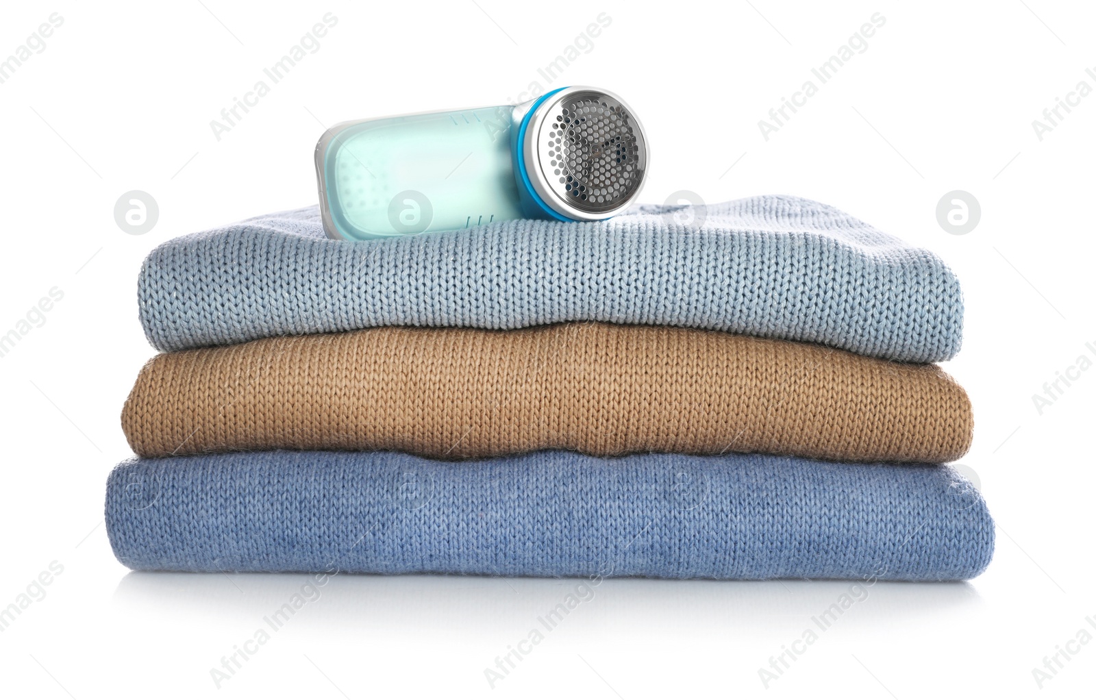 Photo of Modern fabric shaver and woolen clothes on white background