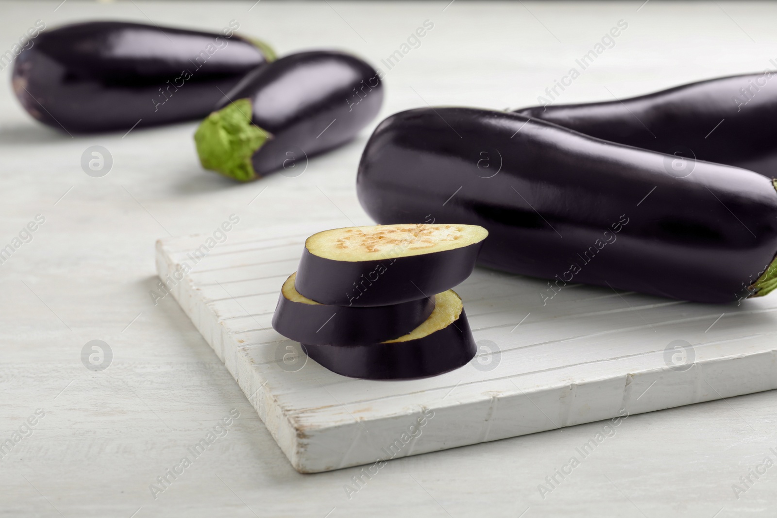 Photo of Wooden board with ripe eggplants on table