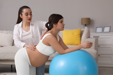Photo of Doula working with pregnant woman in living room. Preparation for child birth